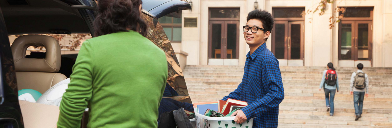 A student moving into a college dorm and unpacking items with his parents