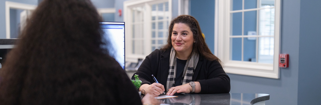 Customer at Thomaston Savings Bank filling out paperwork with teller at desk
