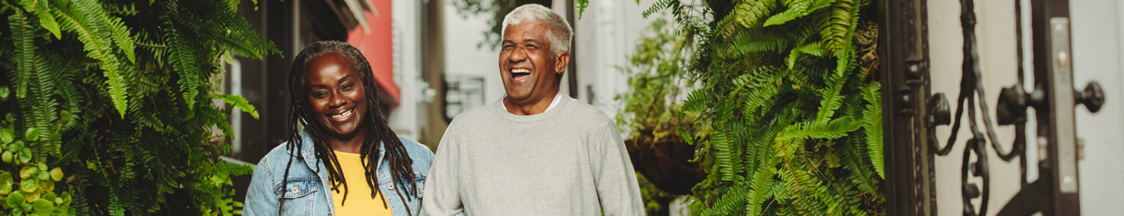 An older couple outside laughing together surrounded by greenery