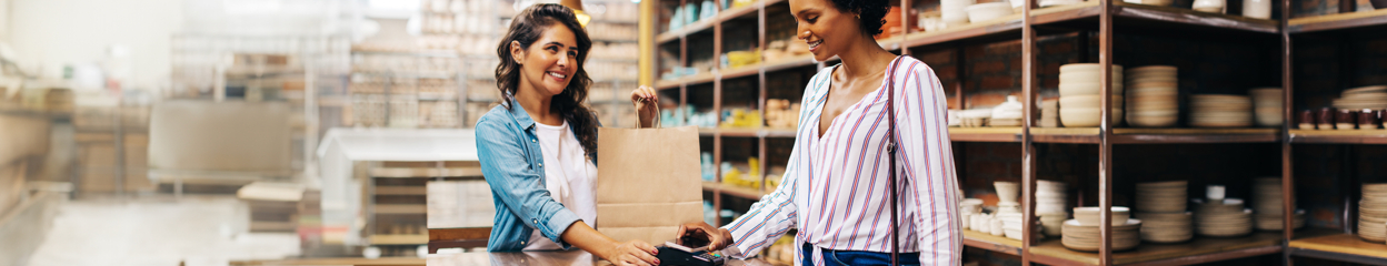 A woman using Mobile Wallet on her cell phone to make a payment while shopping in a store