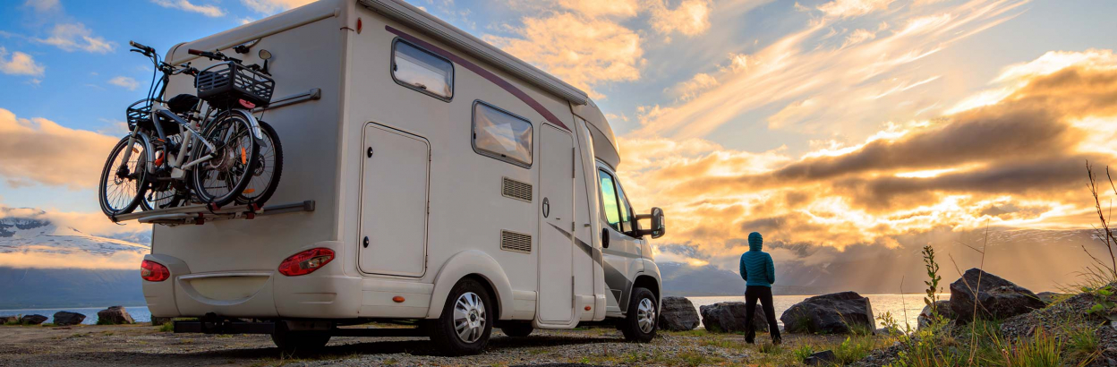 a person looks out into the sunset next to a camper van