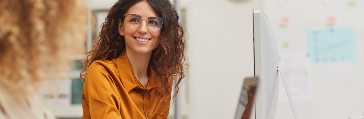 Two female colleagues interacting while working in an office