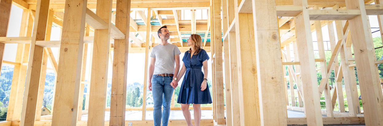 A couple holding hands walking through early construction of their new home