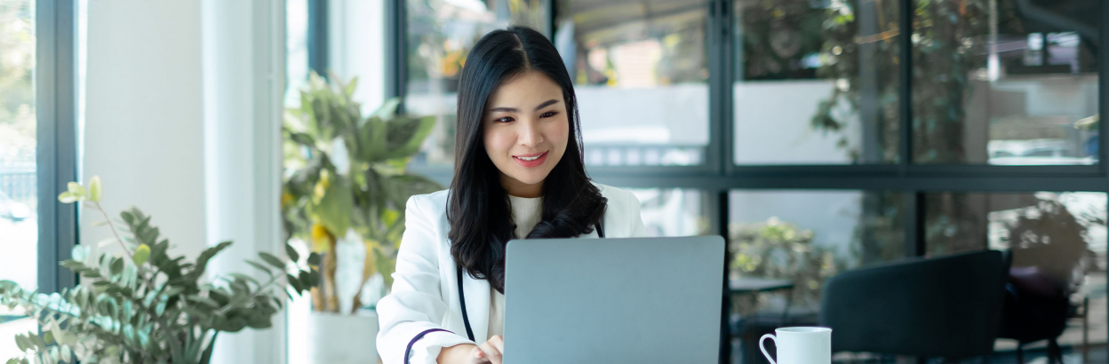 Businesswoman sitting at desk using laptop in an office space