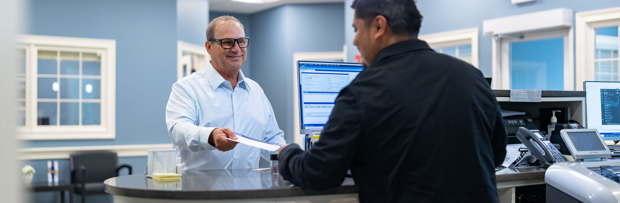 Man depositing a check with a bank teller in the lobby of a Thomaston Savings Bank branch