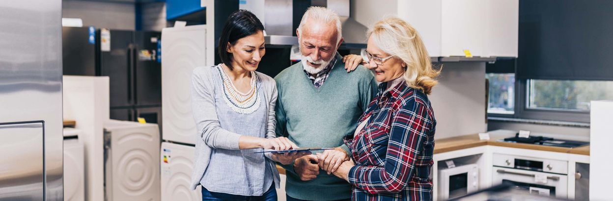 A couple shopping for new kitchen appliances in store with sales person