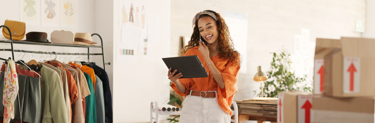 Business woman talking on smartphone with tablet working in her store and checking inventory