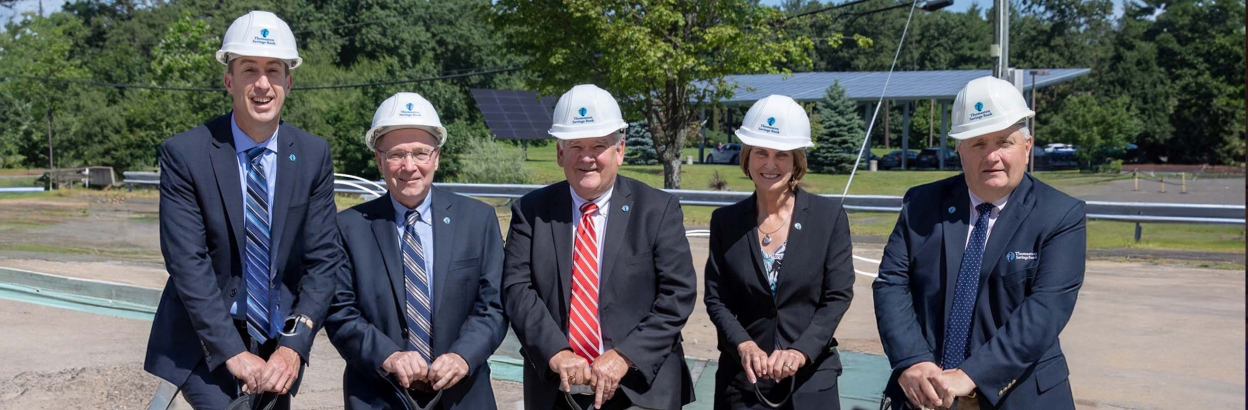Thomaston Savings Bank executives wearing hardhats and holding shovels at a dig site.