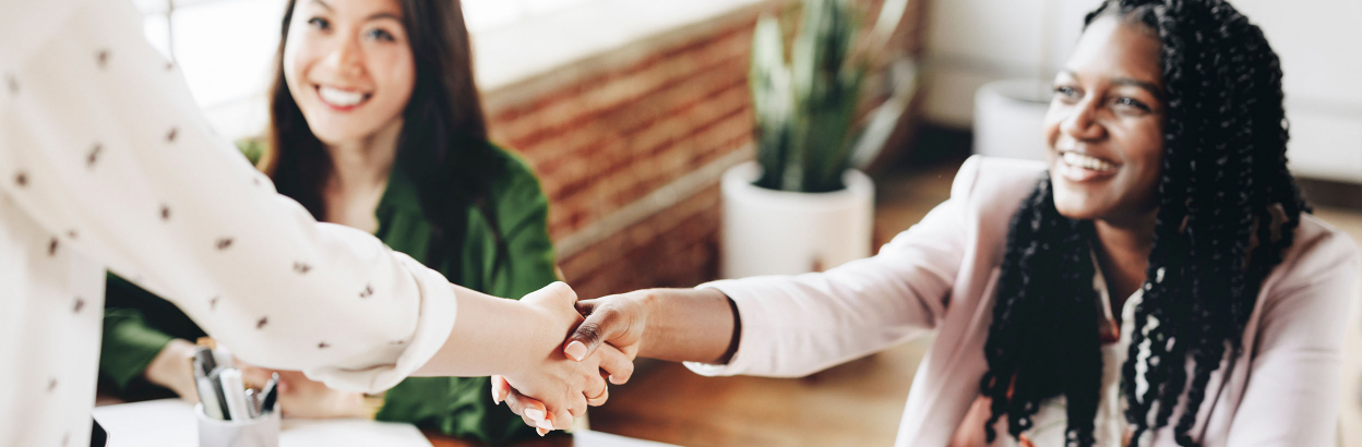 Woman shaking hands with another woman in a business meeting, smiling