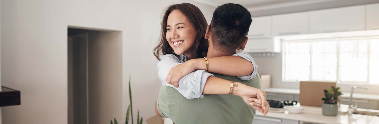 A woman embraces her partner while standing in new home