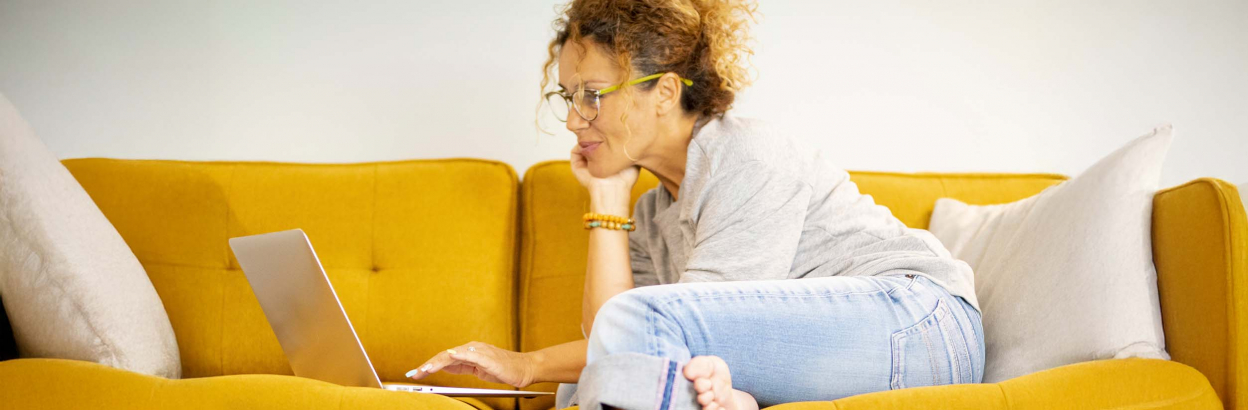 woman on couch using laptop to plan a trip