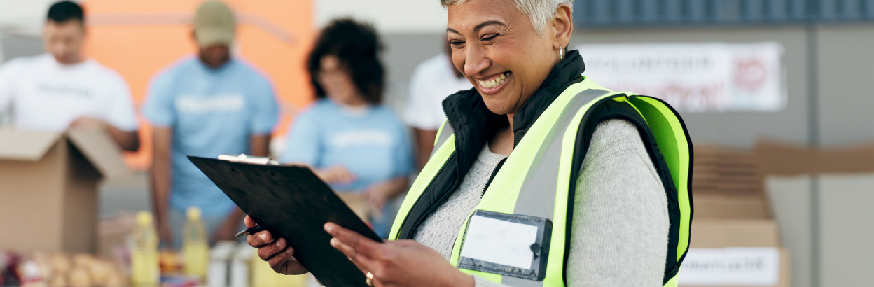 Happy woman leading a food donation project and reading clipboard