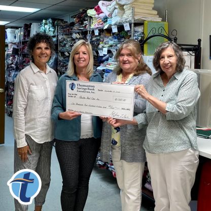 Quilts That Care members hold a big check awarded by Thomaston Savings Bank.